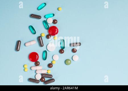 Differenti pillole e compresse multicolore su sfondo blu. Foto Stock