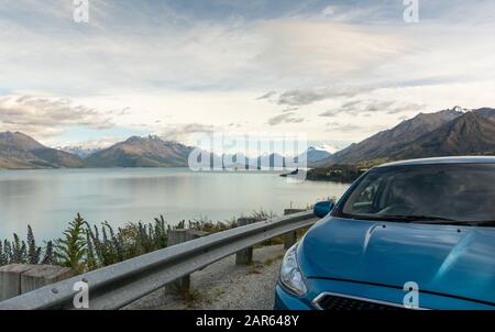 Un'auto blu parcheggiata presso una vista panoramica sul Lago Wakatipu, Nuova Zelanda Foto Stock