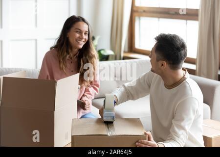 Scatole di imballaggio sorridenti giovane coppia con nastro adesivo Foto Stock