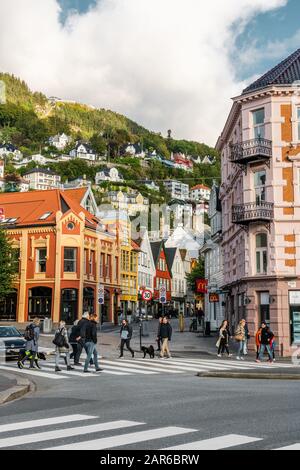 Editoriale 09.03.2019 Bergen Norvegia, attraversamento di strada a Bryggesporden con persone e traffico automobilistico e le montagne sullo sfondo Foto Stock