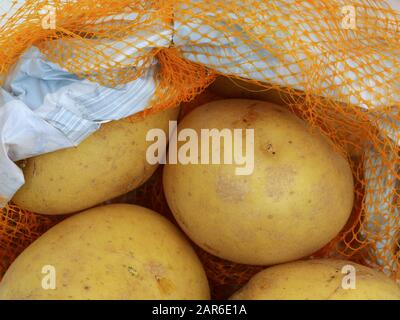 Patate in un sacchetto di rete arancione o in un pacchetto di plastica, primo piano Foto Stock