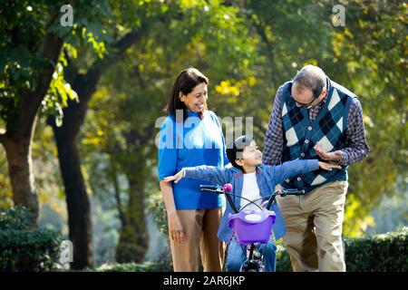 Nonni con nipote imparare a guidare la bicicletta Foto Stock