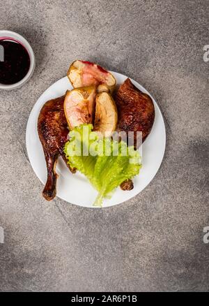 Gamba di anatra arrosto con mele su un piatto. Vista dall'alto. Foto Stock