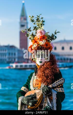 Fantasiosa maschera in splendido costume al carnevale di Venezia. Le persone dietro non sono più riconoscibili e celebrare il carnevale tradizionale di Foto Stock