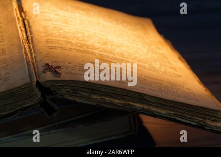 Primo piano Croce cristiana dorata su un vecchio libro. Foto Stock