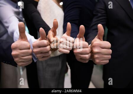 Primo piano multirazzial business persone che mostrano pollici in su gesto. Foto Stock