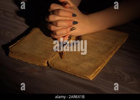 Pregare con Dio, piegare mani di donna cristiana con la sacra bibbia e rosario. Foto Stock