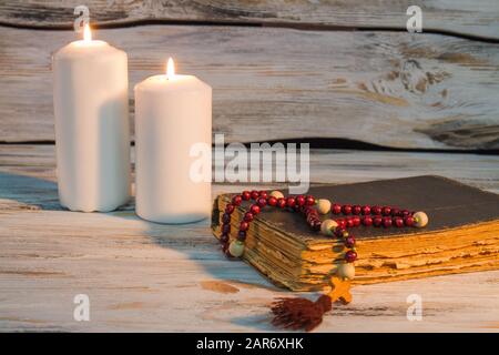 Due canlde brucianti e Santa bibbia con rosario. Foto Stock