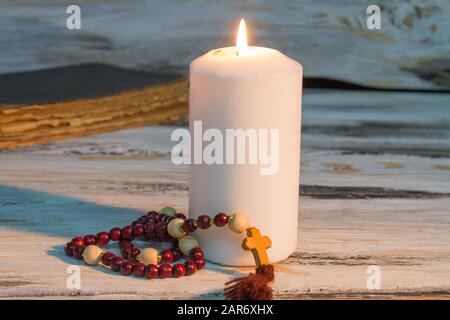 Candela bianca e rosario. Foto Stock