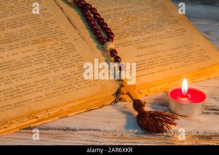 Apri antico manoscritto con rosario e piccola candela. Foto Stock