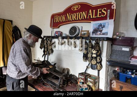 Drayman, Roger Hughes controlla l'imbragatura dei cavalli nella stanza di virata stabile prima delle consegne di birra ai Ganci della famiglia Norton Brewery fondata in Foto Stock