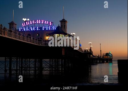 Brighton Palace Pier con il suo cartello illuminato al tramonto. Il famoso molo è una delle attrazioni turistiche più visitate del Regno Unito. Foto Stock