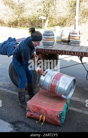 Erzsebet Csak, un assistente di consegna di dray, carica un barile di birra su un grande cuscino dal dray in uno dei pub del villaggio, il Pear Tree, uno shor Foto Stock