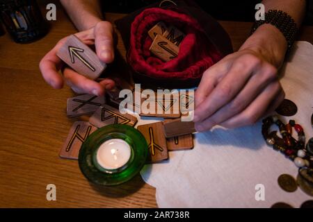 Mani di una donna matura tenere rune Teiwaz significa potere maschile. Fortune raccontare le rune Foto Stock