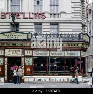 London 1970s, shopping elegante coppia, James Smith & Sons ombrelli e bastoni negozio, New Oxford Street, Inghilterra, Regno Unito, GB, Gran Bretagna, Foto Stock