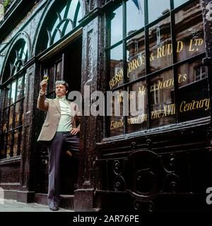 London 1970s, MAN esamina un bicchiere di vino sherry al di fuori del negozio di vendita di vini Berry Bros. & Rudd, St James Street, Inghilterra, Regno Unito, GB, Gran Bretagna, Foto Stock