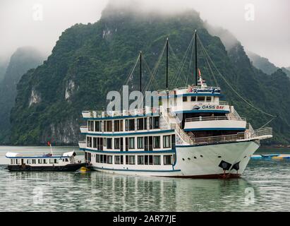 Nave da crociera Oasis Bay con tender in maltempo con colline calcaree, Halong Bay, Vietnam, Asia Foto Stock