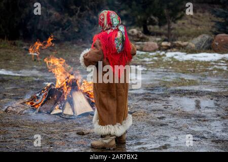 Una ragazza in un nazionale scialle russe e cappotto di pelliccia è vicino ad un fuoco Foto Stock