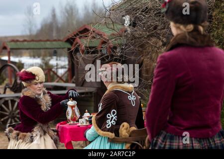 Persone in abbigliamento 19th secolo bere tè da un servizio di tè in natura in un nobile maniero in Russia. Ricostruzione storica Foto Stock