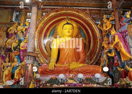 Figure dai colori vivaci che fiancheggiano una grande statua del buddha seduto nel Tempio di Gangaramaya, Colombo, Sri Lanka Foto Stock