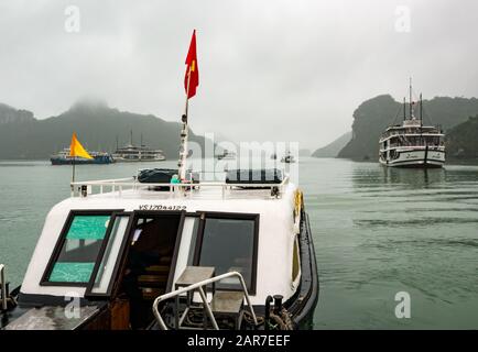 Navi da corsa e da corsa per passeggeri in caso di nebbia con formazioni carsiche calcaree, Halong Bay, Vietnam, Asia Foto Stock