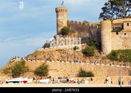 TOSSA DE MAR, SPAGNA - 7 AGOSTO 2019: Un'antica fortezza sulla spiaggia, turisti su una spiaggia di sabbia ai piedi. Foto Stock