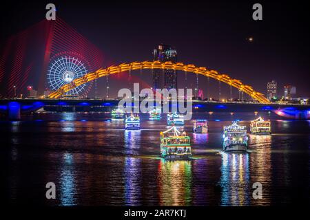 Barche turistiche che si muovono sotto il ponte del Drago alla fine del fuoco Breathing Show, da Nang Vietnam Foto Stock