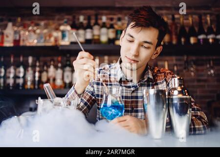 Il barman mescola il cocktail con il colorato bancone del bar con cocktail alcolici Foto Stock