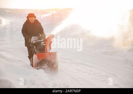 Uomo pulizia neve da marciapiedi con motoslitta inverno Foto Stock