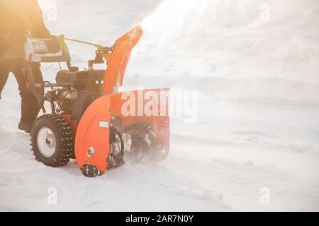 Uomo pulizia neve da marciapiedi con motoslitta inverno Foto Stock