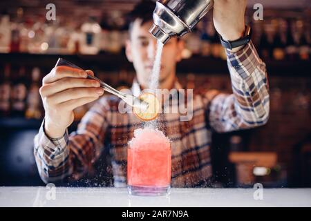 Il barman mescola il cocktail con il colorato bancone del bar con cocktail alcolici Foto Stock