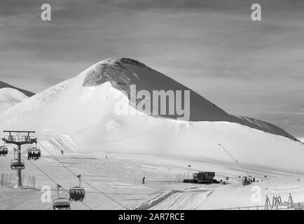 Snowy ski via preparate con neve macchina grooming, seggiovia, cannoni da neve e il gatto delle nevi in ski resort. Montagne nella soleggiata giornata invernale. Alpi italiane. Foto Stock