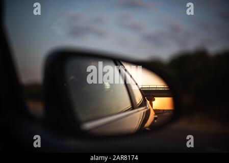 tramonto vivace riflessione vista attraverso l'auto specchio laterale spazio autostrada per il viaggio di testo divertimento famiglia concetto Foto Stock