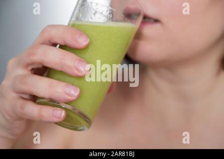 Donna beve succo fresco, bicchiere da primo piano in mani femminili. Concetto di dieta sana, vitamine naturali per la pelle da sedano o kiwi Foto Stock