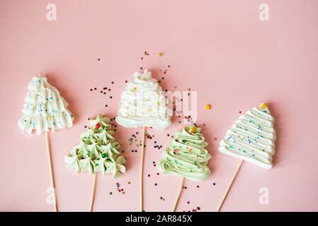 Dolce albero di Natale meringhe in bianco su uno sfondo rosa con bagliori. Concetto di vacanza Foto Stock