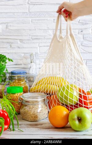 Sacchetto in cotone a rete per alimentari con frutta e verdura. Zero sprechi, nessun shopping di plastica. Concetto di stile di vita sostenibile. Riciclaggio. Foto Stock