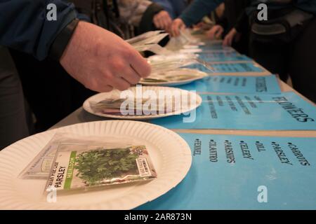 Le persone selezionano i semi da portare a casa all'apertura della libreria di condivisione dei semi, parte della biblioteca pubblica di Eugene, Oregon, USA. Foto Stock