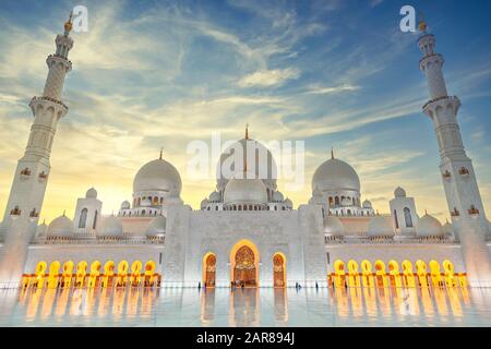 Vista della Grande Moschea di Sheikh Zayed al tramonto in colori luminosi. Aspetto frontale Symertrical Foto Stock