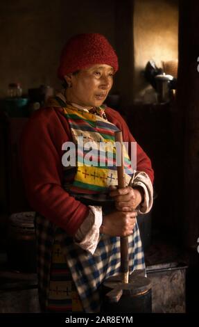 La donna bhutanese sta curando il burro di yak nella sua casa colonica, la valle di Ura, il Bhutan, l'Asia Foto Stock