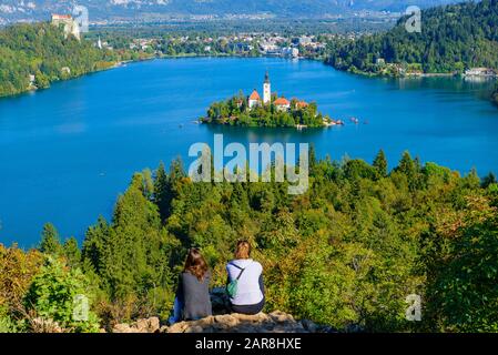 Due persone al Colle Osojnica guardano la vista dell'Isola di Bled e del Lago di Bled, una popolare destinazione turistica in Slovenia Foto Stock