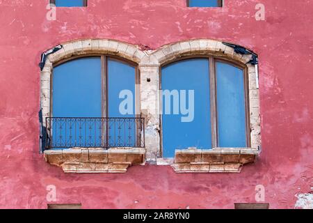 Grandi finestre con balcone ad arco su una parete rossa di un edificio sulla cima di Eivissa (Ibiza Town), Ibiza, Isole Baleari Foto Stock