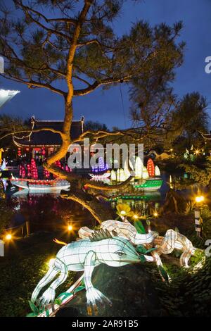 Lanterna illuminata di salamandra e Pinus - Pino con il Padiglione Friendship Hall presso il lago Dream durante l'anno Mostra Magic of Lanterne Foto Stock