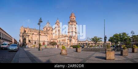 Morelia, Michoacan, Messico - 24 novembre 2019: La gente si gode la mattina al Menchor Ocampo plaza, con la Cattedrale di Morelia in background Foto Stock