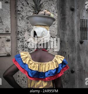 Las Palenqueras, bella signora colombiana che sta camminando e vendendo frutti per le strade di Cartagena. I frutti sono in cima al suo avuto. Foto Stock