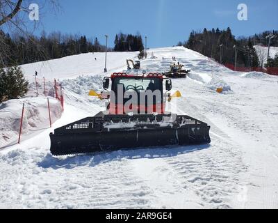 Saint-Sauveur, Canada - 11 aprile 2019: Macchina per la cura della neve in una soleggiata giornata primaverile. Sommet Saint Sauveur è una stazione sciistica di Quebec con un sacco di piste, Foto Stock