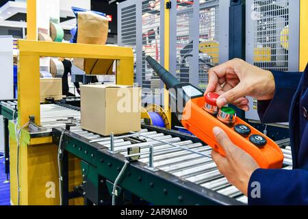 Il responsabile controlla e controlla le scatole di cartone automatiche sul nastro trasportatore nel magazzino di distribuzione. Foto Stock