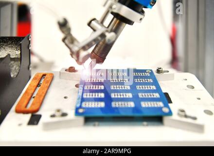 Robot automatico moderno e ad alta tecnologia per la macchina di assemblaggio di schede a circuito stampato (PCB) durante la saldatura o la saldatura di parti o componenti in fabbrica Foto Stock