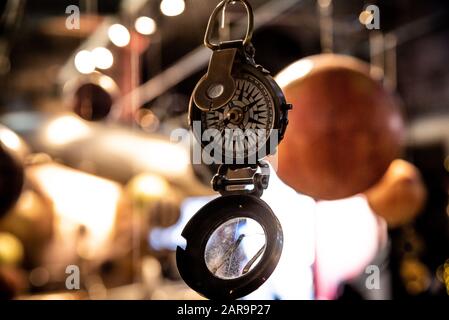 Bellissimo bokeh di fondo di una bussola appeso con luci e riflessioni in background. Concetto di essere perduti, libertà e ricerca della felicità. Foto Stock