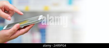 Farmacista usando il cellulare smart phone per la barra di ricerca in esposizione in farmacia farmacia scaffali background.Online Medical Concept. Foto Stock