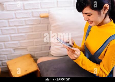 Ragazza teen asiatica felice che tiene un telefono intelligente e una carta di credito a casa - consumatore teenager che compra i prodotti attraverso il concetto in linea di e-commerce Foto Stock